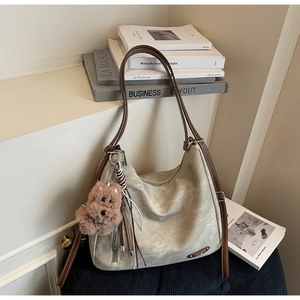 Detail of grey tote bag with brown handles and a cute puppy plush charm on a desk