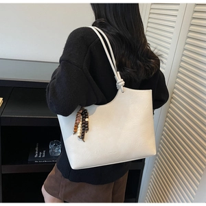Detail of cream tote bag with lychee texture leather and colorful wooden bead pendant