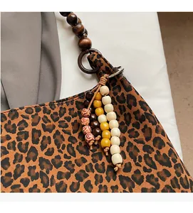 Detailaufnahme der Leopardenmuster-Stofftasche mit Holzperlengriff und Quastenanhänger