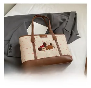 Détail du sac cabas en toile avec pois roses, anses en cuir marron et broderies