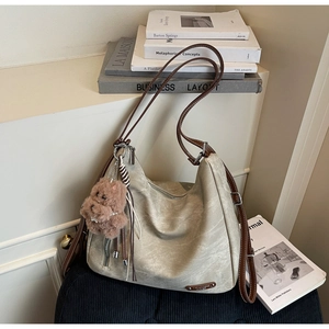 Detail of a large capacity tote bag with brown straps and a cute plush teddy bear charm