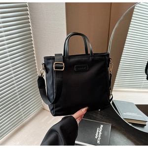 Detail view of black nylon crossbody bag with gold metal buckles and adjustable strap