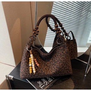 Nahaufnahme der Leopard-Schultertasche mit braunen Holzperlen-Griffen und Perlenanhängern