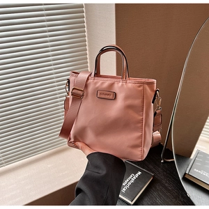 Detailed shot of pink nylon crossbody bucket bag with textured gold hardware and wide strap