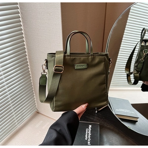 Detail of dark green nylon tote bag with adjustable strap and golden logo hardware