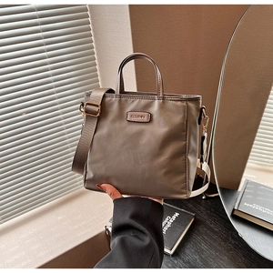 Detail of coffee brown nylon tote bag with metal logo and wide adjustable strap