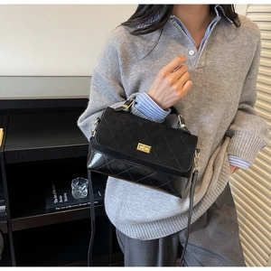 Detail einer schwarzen Stepptasche mit goldener Schnalle und Lederriemen am Modell