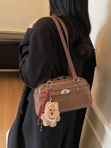 Retro brown leather shoulder bag for women with a cute plush bear charm in office setting