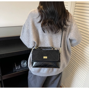 Schwarze Stepptasche mit goldenem Schloss in stilvoller Wohnumgebung gezeigt