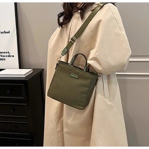 Close-up of olive green nylon handbag with adjustable wide strap and metallic logo plate
