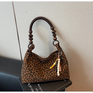 Detail der Wildleder-Tragetasche mit Leopardenmuster, Holzperlengriff und bunter Quaste