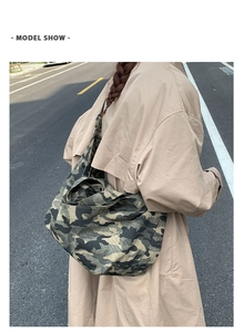 Outdoor street shot of a large capacity camouflage canvas shoulder bag worn by a model