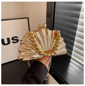Détail de la pochette dorée en forme de coquillage avec poignée en perles et miroir