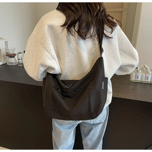 Detailed back view of a black minimalist nylon crossbody bag with adjustable strap and label