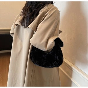 Dettaglio borsa hobo in pelliccia nera abbinata a un trench color kaki classico