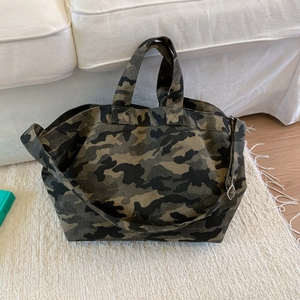 Detailed macro view of camo canvas tote showing adjustable strap and metal buckle detail