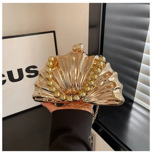 Détail d'un sac de soirée coquillage doré brillant avec poignée perlée et chaîne