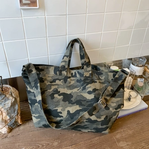 Detail of green camouflage canvas tote bag with adjustable strap on a rustic wooden desk
