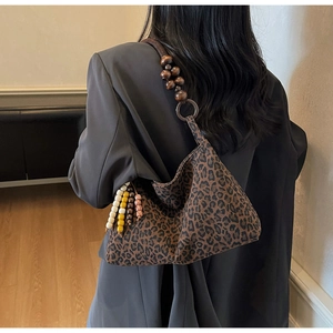 Détail d'un sac léopard avec bandoulière en perles de bois et accents colorés