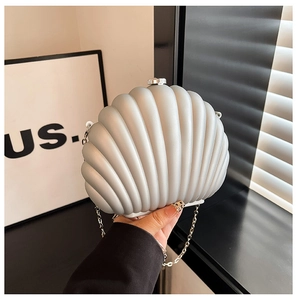 Détail d'une pochette argentée en forme de coquillage avec texture et chaîne en métal