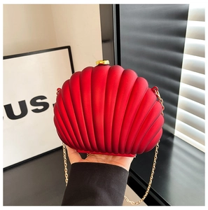 Détail du sac de soirée rouge en forme de coquillage avec chaîne dorée et texture rayée