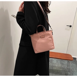 Detailed shot of pink nylon crossbody bucket bag showing texture and brand label