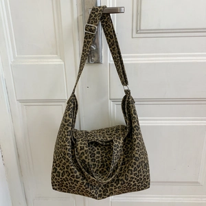 Detail showing adjustable strap and metal buckle on leopard print canvas tote bag