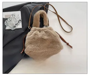 Detail of light brown faux fur bucket bag featuring drawstring closure and leather strap