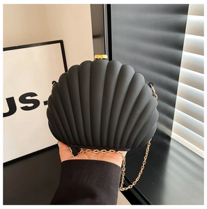 Détail d'un sac en acrylique noir en forme de coquille avec chaîne dorée et texture
