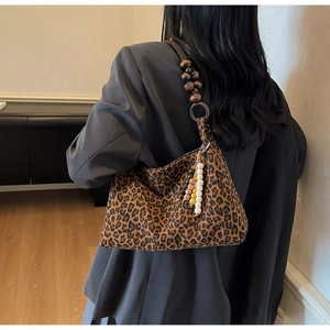 Détail du sac léopard en daim avec sa bandoulière unique en perles de bois foncé