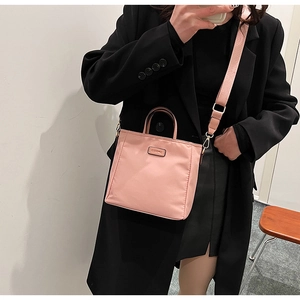 Detailed close-up of a pink nylon tote bag with adjustable strap and metal logo plate