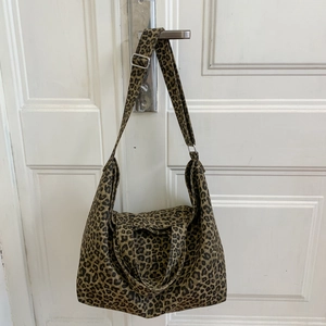 Detail of adjustable strap and leopard print canvas tote bag on a white door