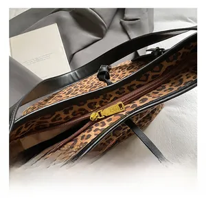 Detail of premium gold-tone metal zipper and leopard print canvas on tote bag