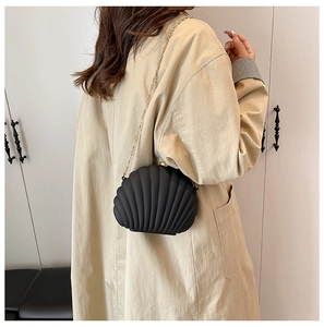 Détail du sac bandoulière noir en forme de coquillage avec chaîne dorée sur mannequin