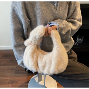 Dettaglio della borsa in peluche beige con manico a nodo tenuta da una modella