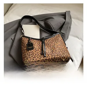 Detail of leopard print hobo bag showing gold metal feet and black leather strap