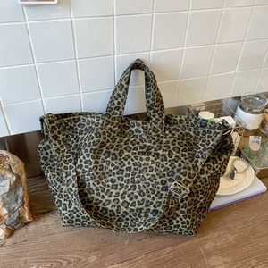 Detail of leopard print canvas tote bag featuring adjustable shoulder strap and handle