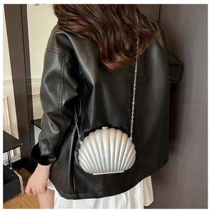 Détail d'un sac bandoulière argenté en forme de coquille avec chaîne métallique