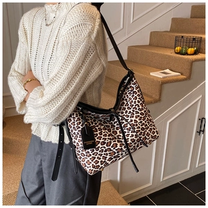 Detail of leopard print tote bag featuring black leather straps and drawstring accents