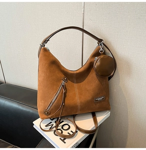 Detail of a brown suede hobo bag with a round coin purse on a magazine background