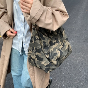 Outdoor lifestyle shot of a large camouflage canvas tote bag with wide shoulder strap