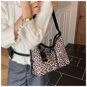 Close-up of leopard print shoulder bag featuring black leather trim and bottom metal studs