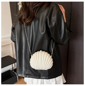 Détail du sac bandoulière coquillage crème avec chaîne argentée porté par le mannequin