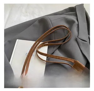 Close-up of brown textured leather bucket bag on a suit jacket for work outfit