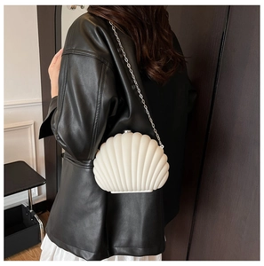 Détail du sac bandoulière coquillage crème avec chaîne argentée porté par un mannequin