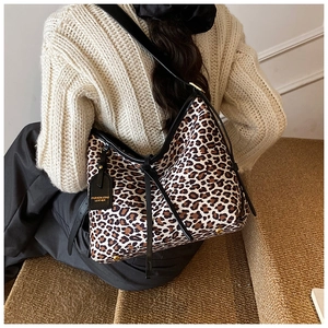 Detail of leopard print tote bag with black leather shoulder strap and fashion tag