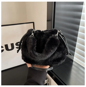 Détail du sac seau en fausse fourrure noire avec poignée en cuir et crochets argentés