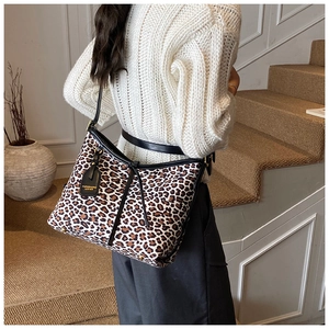 Detail of leopard print tote bag with black leather straps and gold stamped tag