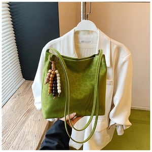Detail of green leopard embossed tote bag featuring a wooden bead tassel and double straps