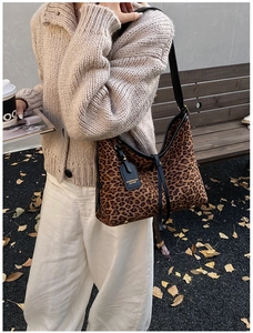 Macro detail of leopard print tote bag featuring black leather trim and fashion brand tag